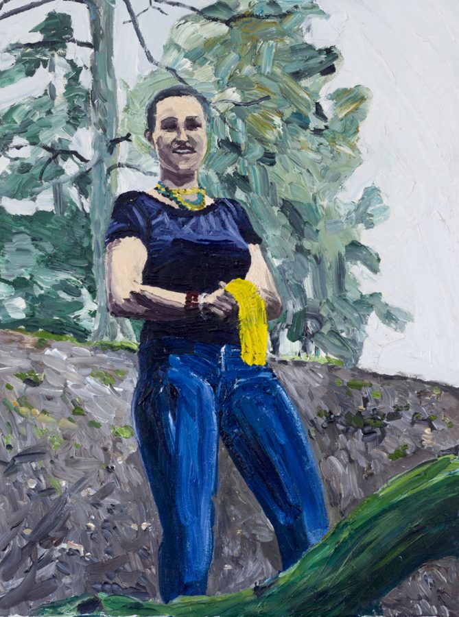 Junge Frau in Jeans und blauem T-Shirt mit gelbem Tuch in der Hand, freundlich lächelnd auf einem Hügel, im Hintergrund ein Tannenbaum